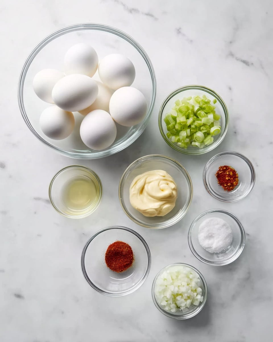 The image shows a clear glass bowl on the left filled with six white eggs. To the right are eight small clear glass bowls arranged in a loose cluster on a white marbled surface. The bowls contain various ingredients: the largest bowl has a dollop of pale yellow mayonnaise; next to it, a small bowl holds finely chopped green celery; another small bowl has a red spice powder; below these, a bowl with a clear liquid sits beside another with a bright yellow mustard. At the bottom, two small bowls contain white granulated substances, likely salt and sugar, and another small bowl holds finely chopped white onions. The scene is bright and clean with the bowls and eggs focused neatly across the white marbled background. Photo taken with an iphone --ar 4:5 --v 7