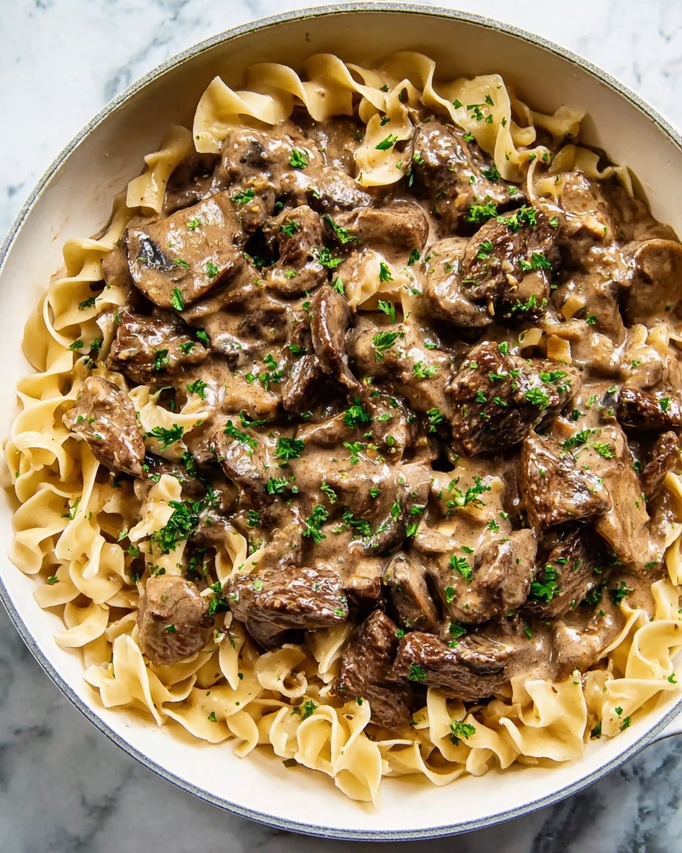A white round pot with two handles holds a creamy light brown sauce base with visible small white beans mixed in, covering the bottom. On top of this sauce, there is a thick layer of dark brown cooked strips of meat arranged loosely in the center, showing a slightly crispy texture on the edges. The pot sits on a white marbled surface which contrasts with the rich colors of the dish. photo taken with an iphone --ar 4:5 --v 7