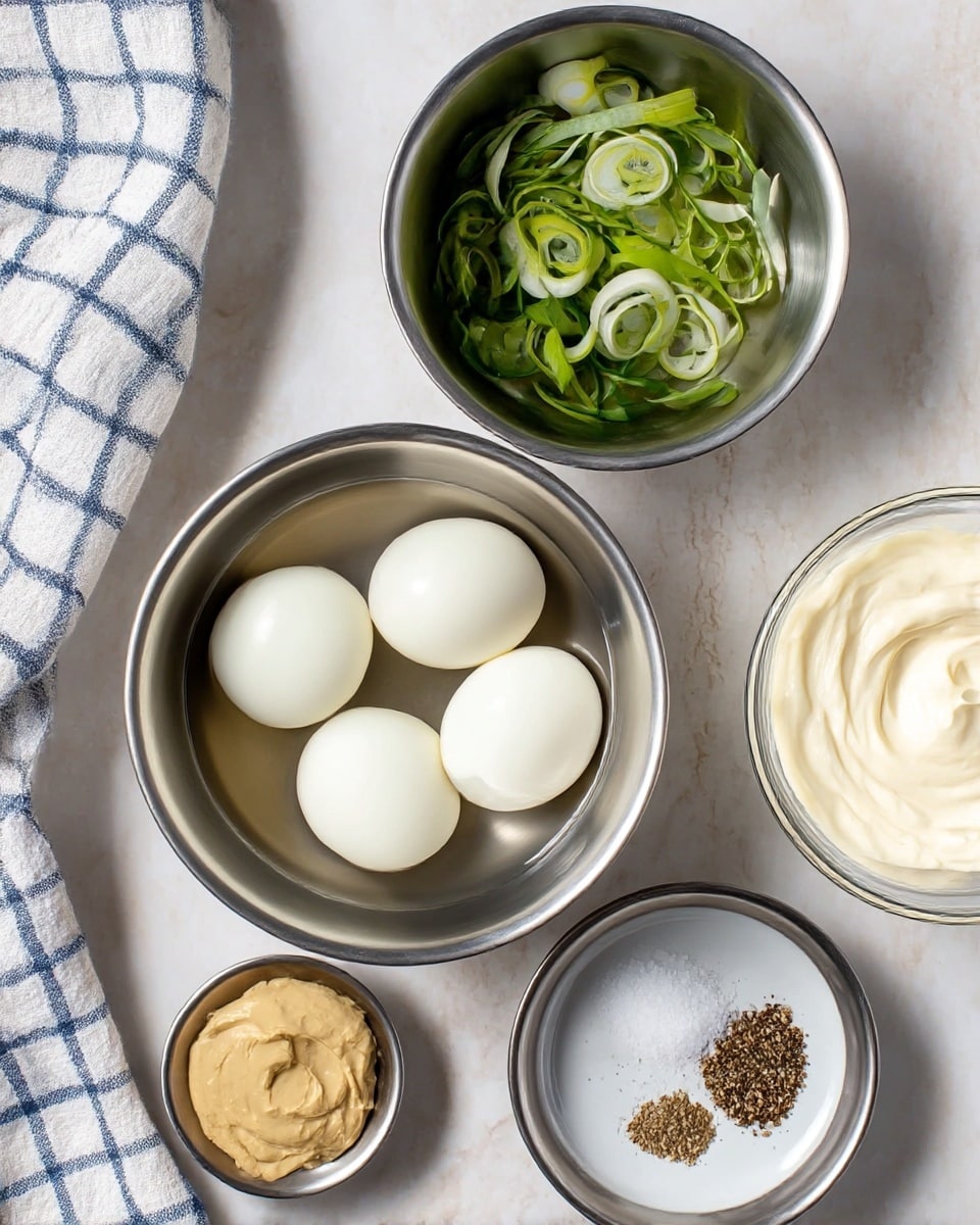 Five peeled hard-boiled eggs sit closely together in a silver metal bowl, with a small amount of water surrounding them. Above this bowl, another silver metal bowl holds sliced green onions, showing bright green and white rings with a fresh texture. To the right, a clear glass bowl contains a creamy white sauce with a smooth, swirled surface. Below, a silver metal bowl holds a small portion of light brown mustard, thick and smooth. Next to it, a small white plate has coarse salt and cracked black pepper scattered on its surface. All the items rest on a white marbled surface, and a white and blue checkered cloth is partially visible in the bottom left corner. photo taken with an iphone --ar 4:5 --v 7