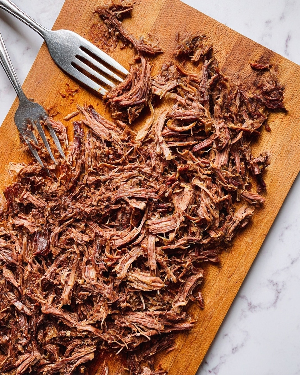 A wooden cutting board filled with shredded cooked meat in dark brown and reddish tones, showing fibrous texture and moist pieces spread evenly across the board. Two silver forks are placed near the top left area, with one fork inserted into the meat pulling it apart. The cutting board is set on a white marbled surface. photo taken with an iphone --ar 4:5 --v 7